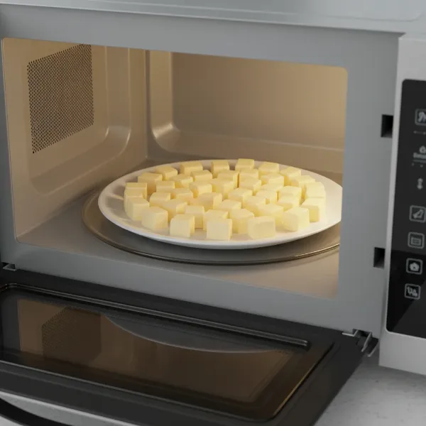 Small, uniform cubes of butter spread on a microwave-safe plate, ready for softening.