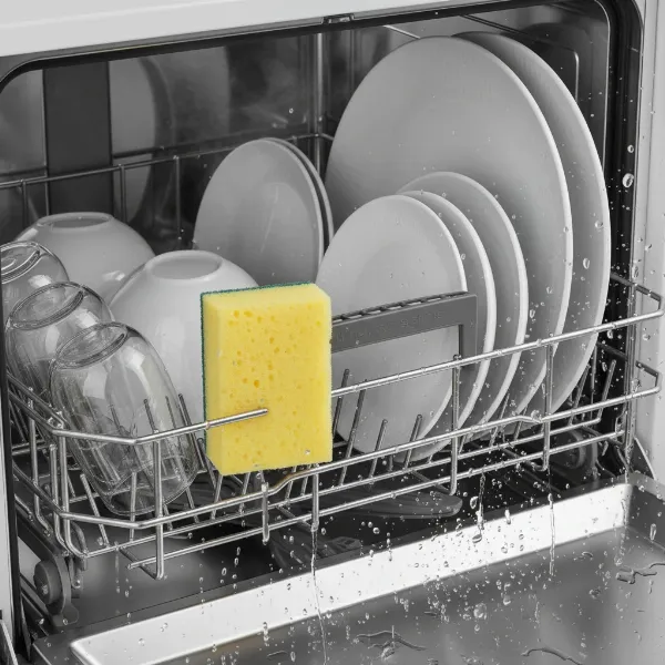 Yellow kitchen sponge placed on the top rack of a dishwasher, undergoing a hot sanitization cycle.