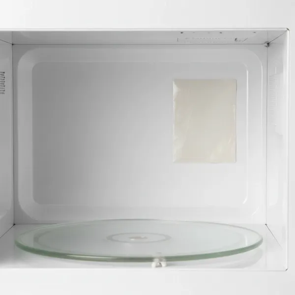 Close-up of a microwave's interior showing the rectangular mica sheet (waveguide cover).