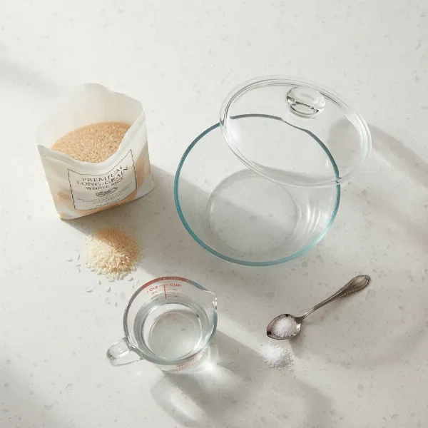 Essential equipment and ingredients for cooking rice in a microwave oven, including a deep bowl.